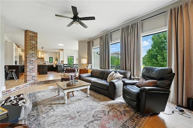 15376 Loring Rd, Bonner Springs, KS 66012 - living area featuring light wood finished floors, plenty of natural light, ceiling fan, and decorative columns