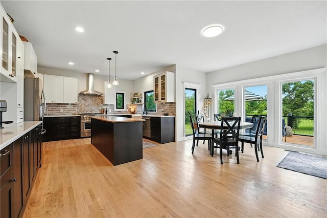 15376 Loring Rd, Bonner Springs, KS 66012 - kitchen featuring wall chimney range hood, stainless steel range, a kitchen island, light countertops, and decorative backsplash