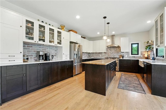 15376 Loring Rd, Bonner Springs, KS 66012 - kitchen with stainless steel appliances, wall chimney range hood, light countertops, light wood-style floors, and a kitchen island
