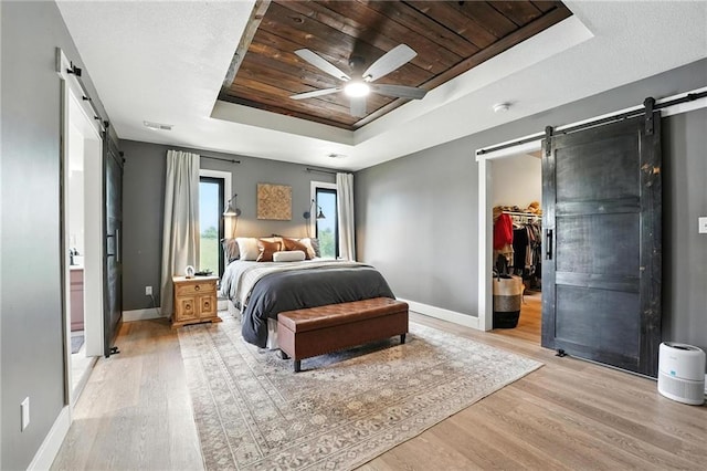 15376 Loring Rd, Bonner Springs, KS 66012 - bedroom featuring a barn door, a raised ceiling, wooden ceiling, light wood finished floors, and a walk in closet