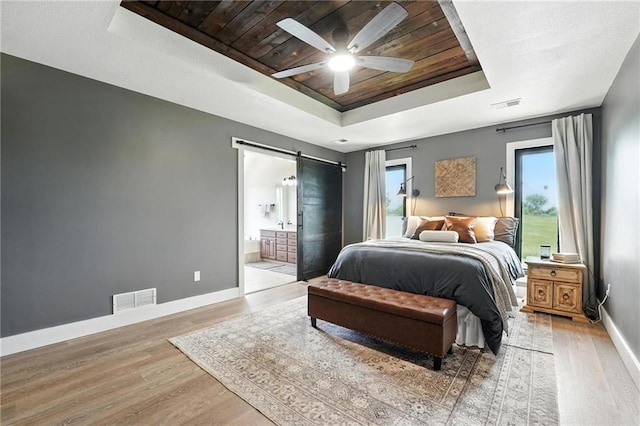 15376 Loring Rd, Bonner Springs, KS 66012 - bedroom with a tray ceiling, wood ceiling, light wood-type flooring, a barn door, and connected bathroom