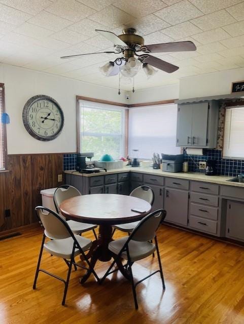 3119 Seneca St, Saint Joseph, MO 64507 - dining space with a ceiling fan, a wainscoted wall, light wood-type flooring, and wood walls