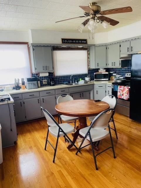 3119 Seneca St, Saint Joseph, MO 64507 - kitchen with appliances with stainless steel finishes, gray cabinets, a ceiling fan, backsplash, and light wood-style floors
