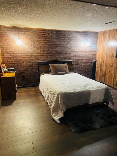 3119 Seneca St, Saint Joseph, MO 64507 - bedroom featuring brick wall, a textured ceiling, and wood finished floors
