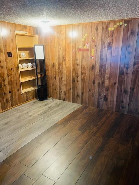 3119 Seneca St, Saint Joseph, MO 64507 - spare room with wood-type flooring, a textured ceiling, and wooden walls