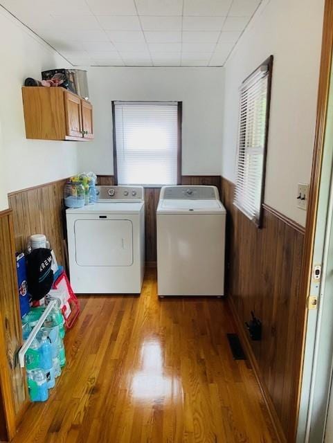 3119 Seneca St, Saint Joseph, MO 64507 - washroom with washing machine and clothes dryer, cabinet space, a wainscoted wall, wood finished floors, and wood walls