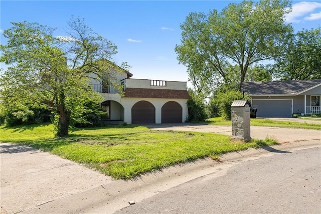 4445 NW 52nd Ter, Topeka, KS 66618 - view of front facade featuring dirt driveway, a front lawn, an attached garage, stucco siding, and a balcony
