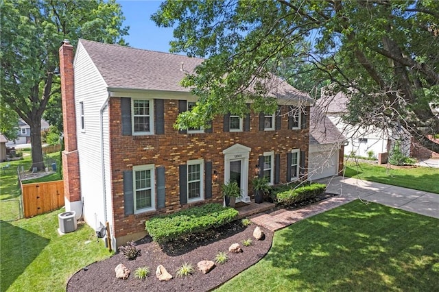 12005 W 100th Ter, Lenexa, KS 66215 - colonial home with concrete driveway, a chimney, brick siding, roof with shingles, and a garage