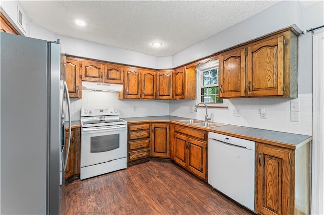 1275 NE Tudor Rd, Lees Summit, MO 64086 - kitchen with white appliances, under cabinet range hood, brown cabinetry, a textured ceiling, and dark wood-type flooring
