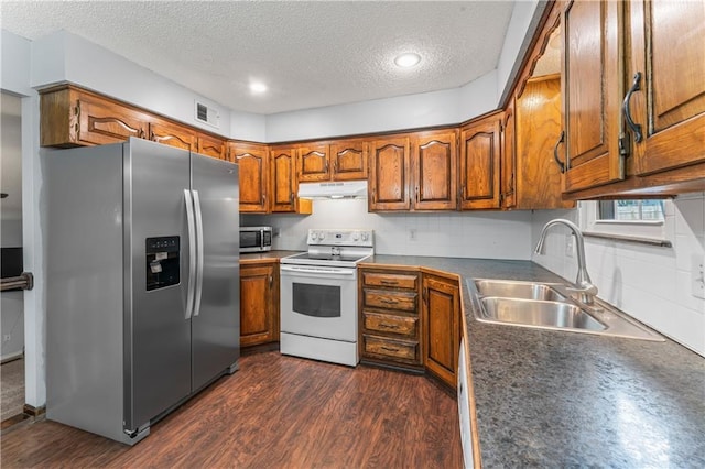 1275 NE Tudor Rd, Lees Summit, MO 64086 - kitchen featuring stainless steel appliances, under cabinet range hood, brown cabinetry, a textured ceiling, and dark wood-style flooring