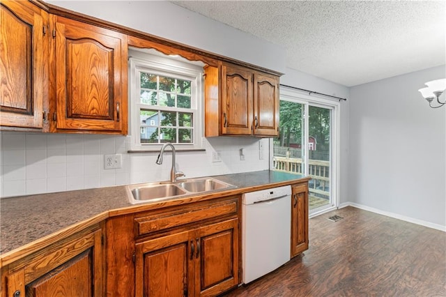1275 NE Tudor Rd, Lees Summit, MO 64086 - kitchen featuring white dishwasher, dark wood finished floors, brown cabinets, backsplash, and a textured ceiling