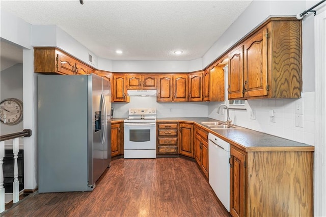 1275 NE Tudor Rd, Lees Summit, MO 64086 - kitchen with white appliances, under cabinet range hood, brown cabinets, dark wood-type flooring, and a textured ceiling
