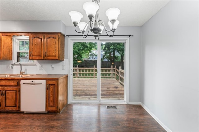 1275 NE Tudor Rd, Lees Summit, MO 64086 - kitchen with dishwasher, a chandelier, brown cabinetry, dark wood-style flooring, and a textured ceiling
