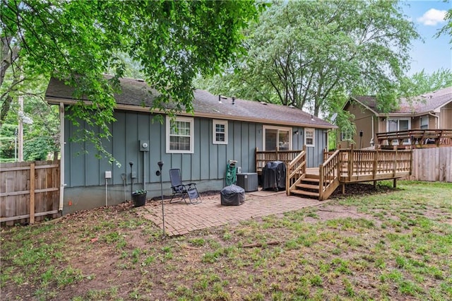 1275 NE Tudor Rd, Lees Summit, MO 64086 - rear view of house featuring board and batten siding, a fenced backyard, a patio area, a wooden deck, and a shingled roof