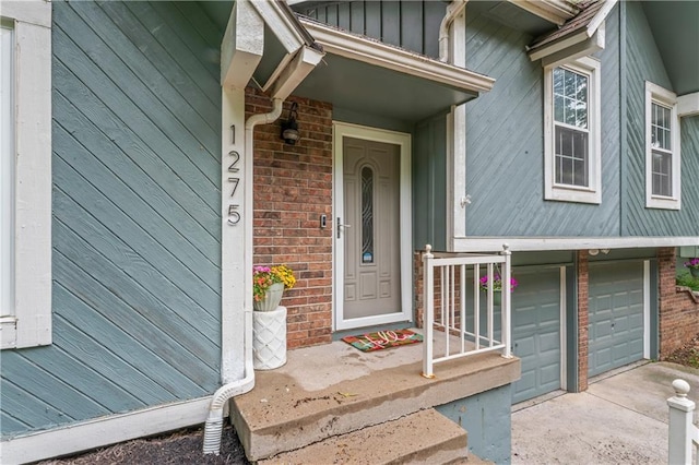 1275 NE Tudor Rd, Lees Summit, MO 64086 - doorway to property with a garage, concrete driveway, brick siding, and board and batten siding