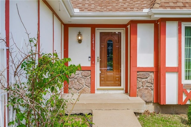 12417 Newton Ct, Grandview, MO 64030 - doorway to property with roof with shingles, stone siding, and stucco siding