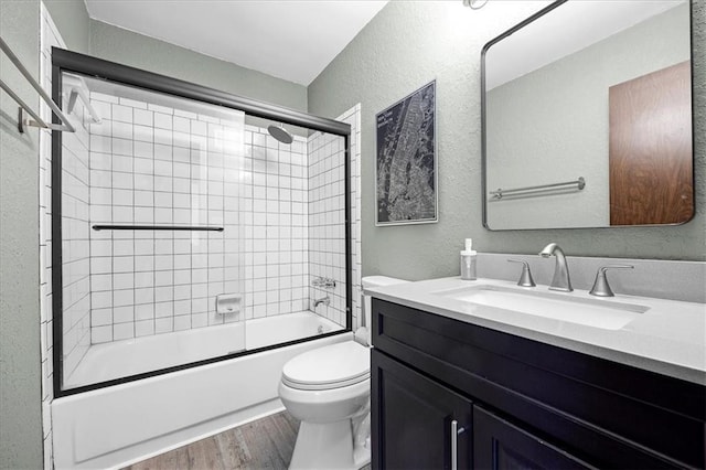 6628 Bradshaw St, Shawnee, KS 66216 - full bathroom with a textured wall, vanity, wood finished floors, and bath / shower combo with glass door