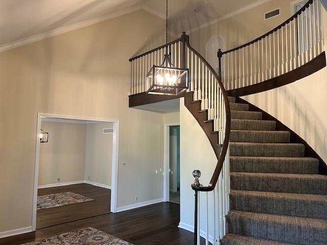 1901 NE River Ridge Rd, Saint Joseph, MO 64507 - stairway featuring wood finished floors, a chandelier, a towering ceiling, and ornamental molding