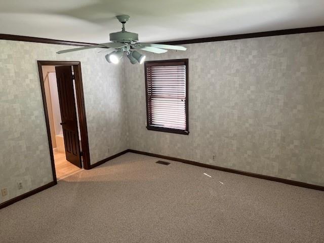 1901 NE River Ridge Rd, Saint Joseph, MO 64507 - spare room featuring light colored carpet, ceiling fan, and crown molding