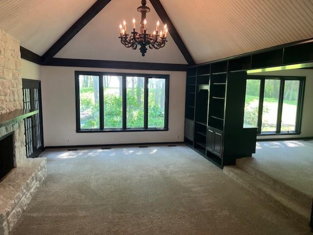 1901 NE River Ridge Rd, Saint Joseph, MO 64507 - unfurnished living room featuring high vaulted ceiling, a chandelier, carpet floors, beamed ceiling, and a fireplace