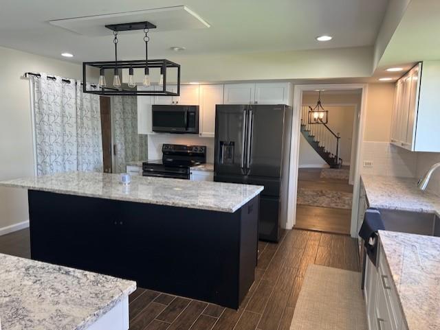 1901 NE River Ridge Rd, Saint Joseph, MO 64507 - kitchen featuring black appliances, dark wood-type flooring, a center island, white cabinets, and light stone counters