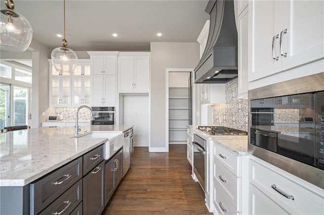 17117 Bluejacket St, Overland Park, KS 66221 - kitchen featuring premium range hood, white cabinetry, appliances with stainless steel finishes, light stone countertops, and decorative backsplash