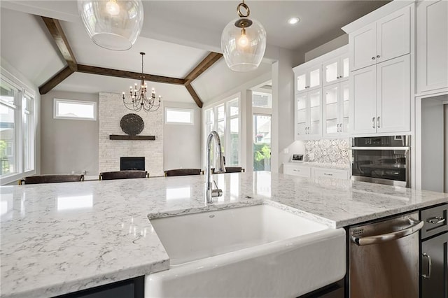 17117 Bluejacket St, Overland Park, KS 66221 - kitchen featuring stainless steel appliances, a fireplace, light stone counters, a chandelier, and hanging light fixtures