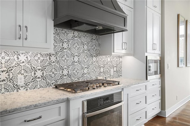 17117 Bluejacket St, Overland Park, KS 66221 - kitchen featuring appliances with stainless steel finishes, premium range hood, decorative backsplash, and white cabinets