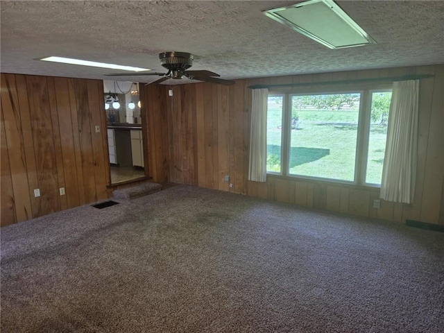 18916 166th St, Basehor, KS 66007 - unfurnished living room with carpet floors, a textured ceiling, wooden walls, and ceiling fan