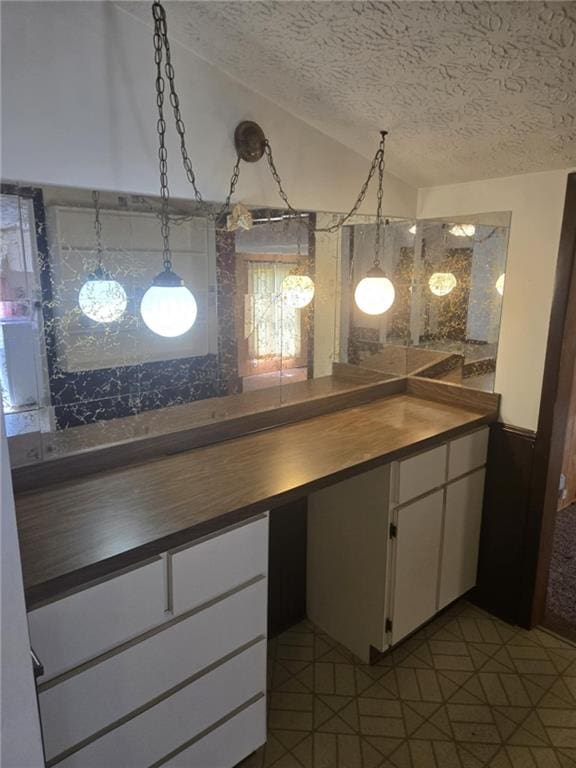 18916 166th St, Basehor, KS 66007 - kitchen with a textured ceiling, lofted ceiling, white cabinetry, butcher block countertops, and dark tile patterned floors
