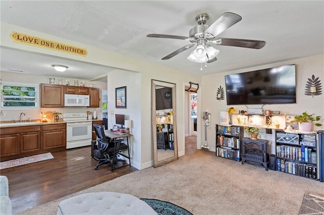 5525 NE Meadowbrook Rd, Kansas City, MO 64119 - living area featuring a wood stove, dark carpet, a ceiling fan, and dark wood-style floors