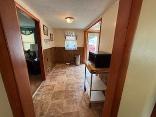 114 S Appleton St, Sugar Creek, MO 64054 - hallway featuring wainscoting, stone finish flooring, wooden walls, and a textured ceiling