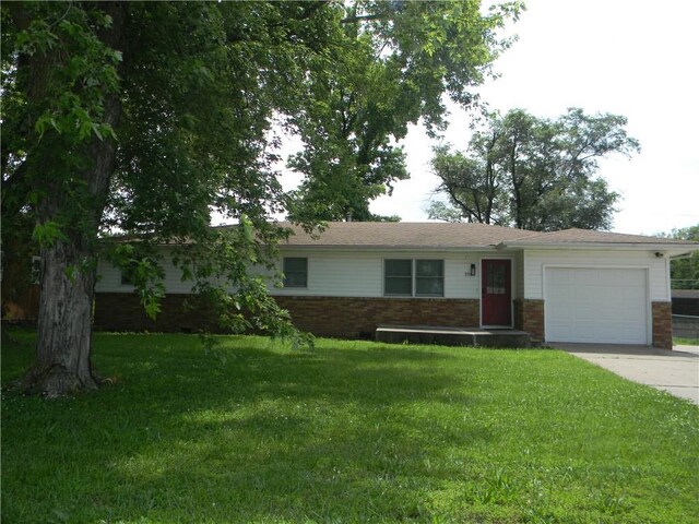 811 E Garfield St, Iola, KS 66749 - ranch-style home with brick siding, a garage, concrete driveway, and a front yard