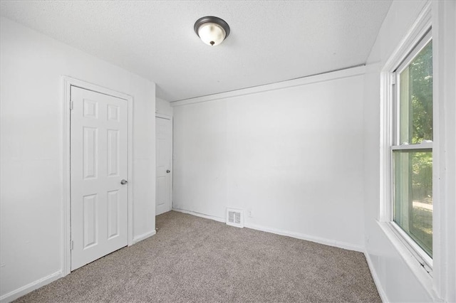 6701 Walrond Ave, Kansas City, MO 64132 - unfurnished bedroom featuring carpet flooring, multiple windows, and a textured ceiling