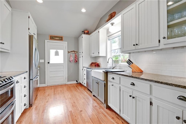 3 M St, Lake Lotawana, MO 64086 - kitchen featuring appliances with stainless steel finishes, tasteful backsplash, light wood-style flooring, white cabinetry, and vaulted ceiling