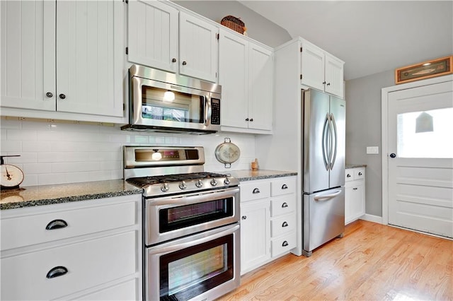 3 M St, Lake Lotawana, MO 64086 - kitchen with appliances with stainless steel finishes, dark stone countertops, backsplash, and light wood-style flooring