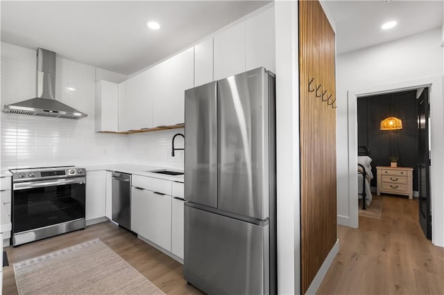 1372 N 150th Rd, Baldwin City, KS 66006 - kitchen with appliances with stainless steel finishes, wall chimney range hood, light countertops, white cabinetry, and light wood-type flooring