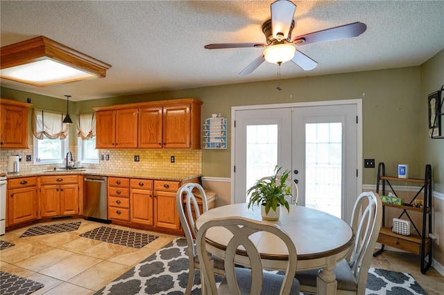 101 Shasta Daisy Dr, Smithville, MO 64089 - kitchen with stainless steel dishwasher, french doors, decorative backsplash, brown cabinetry, and a textured ceiling