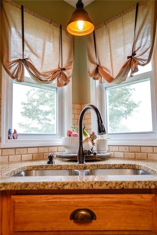 101 Shasta Daisy Dr, Smithville, MO 64089 - kitchen view of decorative backsplash, brown cabinetry, hanging light fixtures, and light stone counters