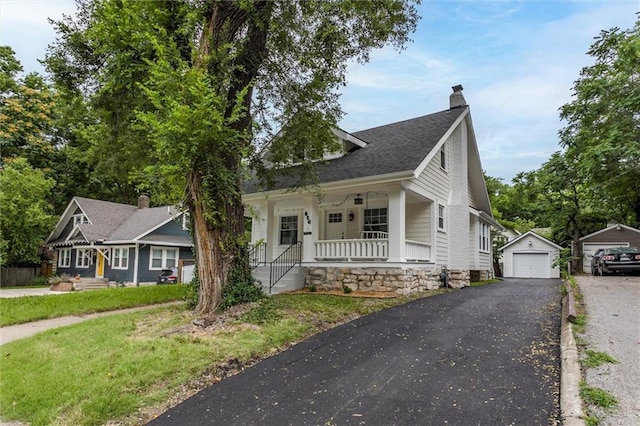 826 W 75th St, Kansas City, MO 64114 - view of front facade featuring a porch, asphalt driveway, a chimney, an outbuilding, and a garage
