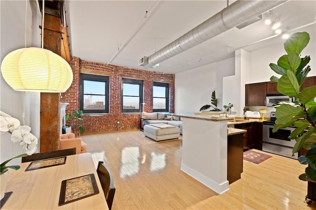 200 Main St Unit 509, Kansas City, MO 64105 - kitchen with appliances with stainless steel finishes, brick wall, a peninsula, light wood-style floors, and open floor plan