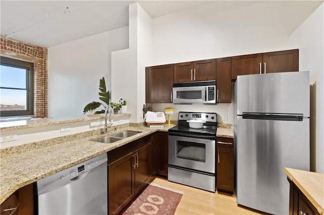 200 Main St Unit 509, Kansas City, MO 64105 - kitchen featuring appliances with stainless steel finishes, light stone countertops, dark brown cabinets, and light wood-type flooring