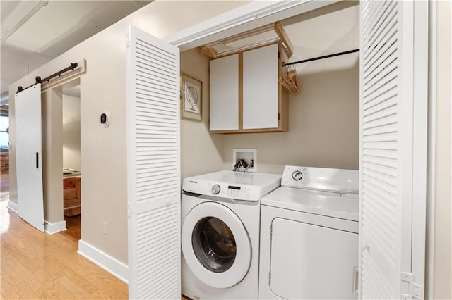 200 Main St Unit 509, Kansas City, MO 64105 - laundry room featuring washing machine and clothes dryer, light wood finished floors, cabinet space, and a barn door