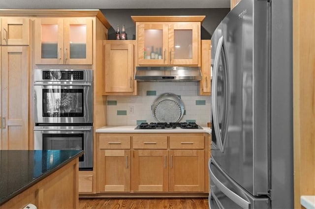 5814 Aminda St, Shawnee, KS 66226 - kitchen with stainless steel appliances, under cabinet range hood, wood finished floors, backsplash, and glass insert cabinets