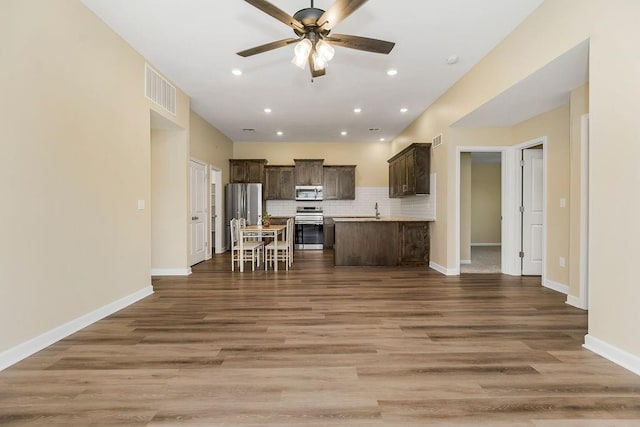 21119 E 8th St S, Independence, MO 64056 - kitchen featuring stainless steel appliances, dark brown cabinets, open floor plan, a ceiling fan, and decorative backsplash