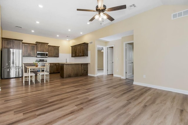 21119 E 8th St S, Independence, MO 64056 - kitchen featuring appliances with stainless steel finishes, dark brown cabinets, open floor plan, ceiling fan, and backsplash