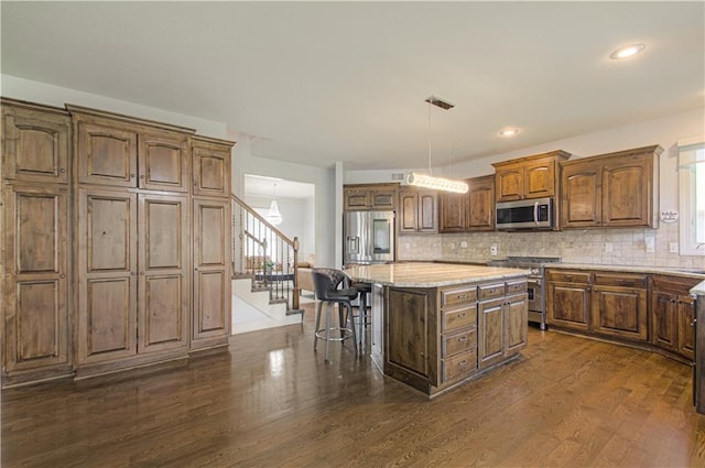 9624 N Arlington Ave, Kansas City, MO 64158 - kitchen featuring stainless steel appliances, a kitchen breakfast bar, a kitchen island, decorative backsplash, and dark wood finished floors