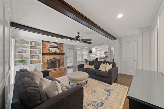 9805 W 121st Ter, Overland Park, KS 66213 - living area featuring dark wood-style floors, beamed ceiling, a ceiling fan, a fireplace, and recessed lighting
