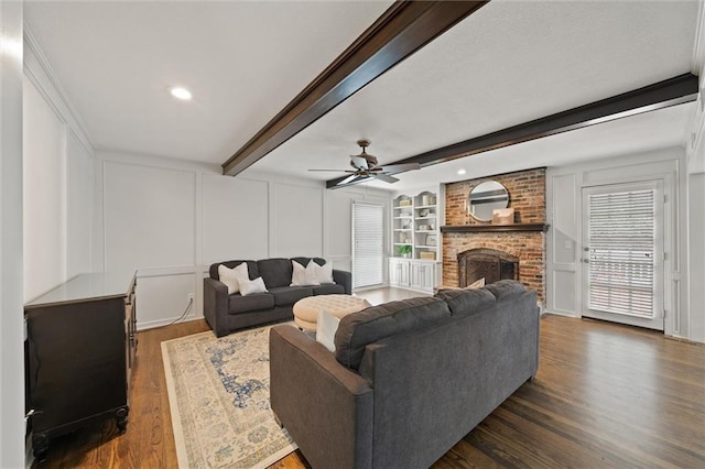 9805 W 121st Ter, Overland Park, KS 66213 - living room with a decorative wall, dark wood-style flooring, beam ceiling, ceiling fan, and a fireplace