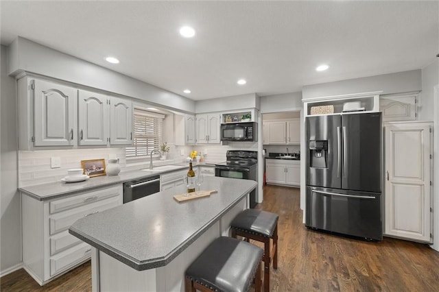 9805 W 121st Ter, Overland Park, KS 66213 - kitchen featuring black appliances, a breakfast bar area, dark wood-style floors, a center island, and recessed lighting